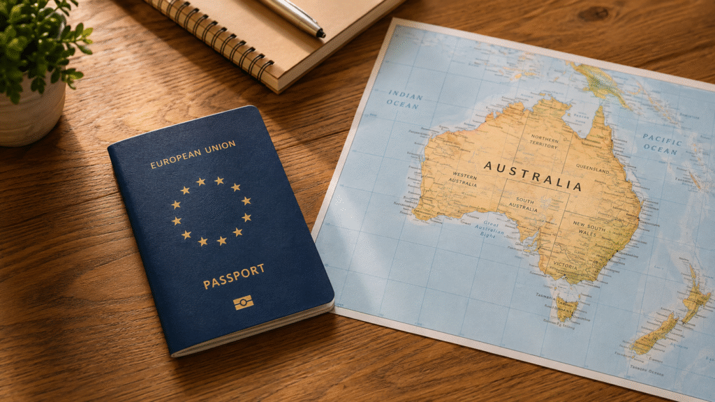 A flat-lay of a European passport (generic blue, no country shown) on a wooden desk next to a map of Australia, warm natural light. Clean and simple.
